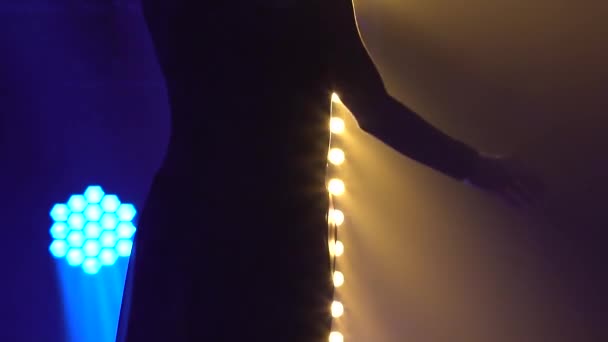 Atraktivní štíhlá tanečnice v černém kostýmu předvádějící kontemplární choreografii v kouřovém studiu s modrým světlem. Silueta pružného těla zblízka. Zpomalený pohyb. — Stock video