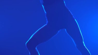 Profesyonel bir dansçı tarafından seslendirilen çağdaş tensel küçümseme koreografisi bir duman ve mavi ışığa karşı. İnce bir kadının silueti, bacakları kapalı. Yavaş çekim.