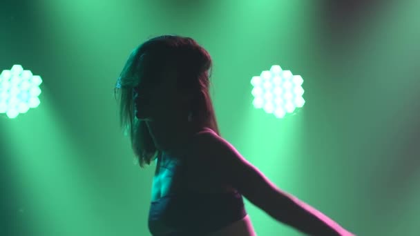 Eine moderne Tänzerin in schwarzen Dessous führt in einem dunklen Studio mit Hintergrundbeleuchtung schöne dramatische Tänze aus Plastik auf. Silhouette einer flexiblen Frau in Nahaufnahme einer sexuell tanzenden Teilnehmerin. Zeitlupe. — Stockvideo