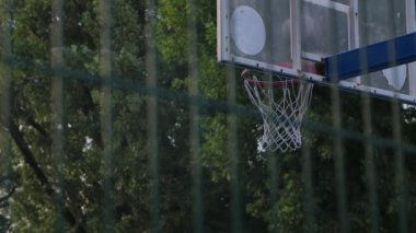 Basketbol sahasının arkasından topların düştüğü çemberin görüntüsü. Parktaki bir spor sahasında çekildi. Kapatın. Yavaş çekim.