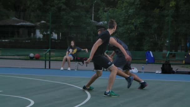 Skilful kille basketspelare i uniform, dribblar bollen, passerar motståndarna försvarare och fullbordar attacken genom att göra poäng bollen från ett kast. Sommarlek. Närbild. Långsamma rörelser. — Stockvideo