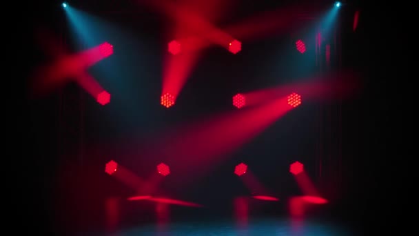 赤い動きのスポットライトと青い光は、暗闇の中の空の段階にあります。舞台照明。ダイナミックな光のショー。ディスコパーティー、結婚式や誕生日のお祝い、ナイトクラブエンターテイメントで輝くライト. — ストック動画