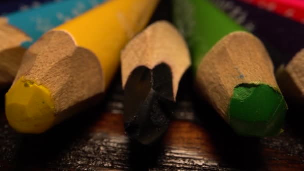 Sok színes ceruza sorakozik. Ceruzát csúsztatok az asztalon. Makró lövés a laowa lencsén. — Stock videók