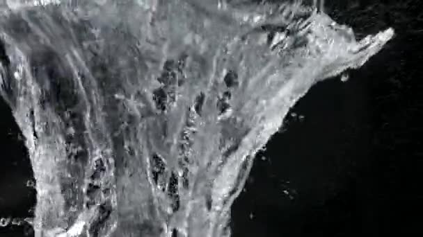 Salpicadura de agua de un objeto que golpea la superficie del agua en cámara lenta. Explosión submarina de cerca sobre fondo negro. — Vídeos de Stock