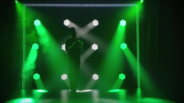 Ένας εθνικός μουσικός παίζει το Αφρικανικό ρυθμικό όργανο shekere και χορεύει στο ρυθμό της μουσικής. Σιλουέτα Αφρο-Αμερικανών σε σκούρο φόντο στούντιο με πράσινα φώτα. Αργή κίνηση. — Αρχείο Βίντεο