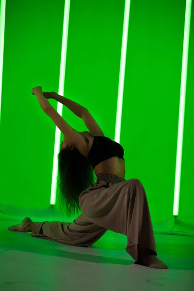 Imagem de uma jovem encantadora posando pelas luzes de néon verde dentro de casa. — Fotografia de Stock