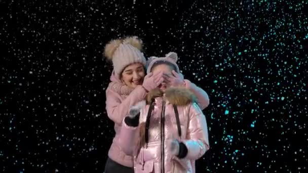 Eerste sneeuw. Gelukkig gezin verheugt zich en knuffelt op een zwarte achtergrond in de studio. Snoeien. Sneeuwvlokken vallen. Nieuwjaar. Kerstvakantie. Langzame beweging. Sluiten.. — Stockvideo