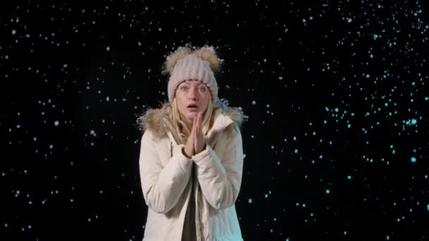 Portrait of a young woman looking into the camera with excitement and then celebrating her victory. The blonde in warm winter clothes against the background of falling snow. Slow motion. Close up. — Stock Video