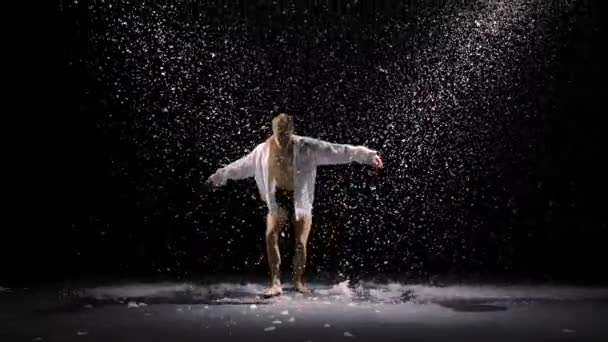 Sensueel hedendaags ballet tegen de achtergrond van langzaam vallende sneeuw. De jongeman beweegt zich soepel tussen de glinsterende sneeuw en studiolicht. Langzame beweging. — Stockvideo