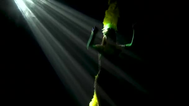 O siluetă întunecată a unei femei zvelte într-un costum de carnaval revelator și o rochie de cap cu pene dansează pe un fundal negru luminat din spate. Close up . — Videoclip de stoc