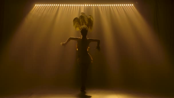 Silhouettes d'une belle danseuse de carnaval en costume jaune et coiffure en plumes. Magnifique femme dansant passionnément la samba en studio sur fond de lumières au ralenti. — Video