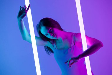 Güzel, doğal yüzlü, göz kamaştırıcı mavi ışıkla odada poz veren güzel, genç bir model. Kapat..