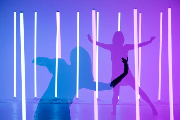 Colagem de sombras dançarina jovem dançando e posando em uma sala com lâmpadas de néon. Um modelo moderno esbelto em um fundo azul roxo. — Fotografia de Stock