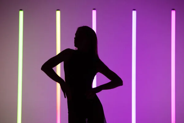 一个性感迷人的年轻女子在紫色工作室背景下与霓虹灯的轮廓。靠近点. — 图库照片