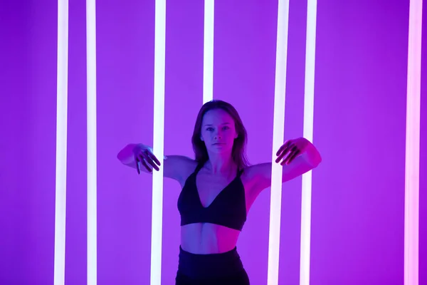 Skinny fashion model dragen zwarte erotische lingerie in kleurrijke heldere neon uv paarse lichten poseren in de studio. Sluiten.. — Stockfoto