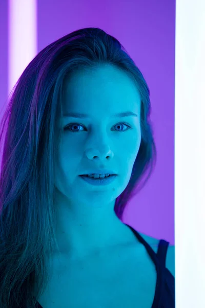 Retrato de estúdio de uma jovem sexy com rosto bonito e cabelos longos no estúdio com luz azul incrível. Mulher atraente posando em uma sala com fundos coloridos e luzes de néon. Fechar. — Fotografia de Stock