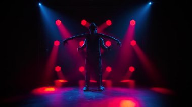 Erkekler akrobatik hareketler sergiler. İki erkek jimnastikçinin profesyonel performansı. Siyah arkaplanda kırmızı ışıklı siluetler. Yavaş çekim.