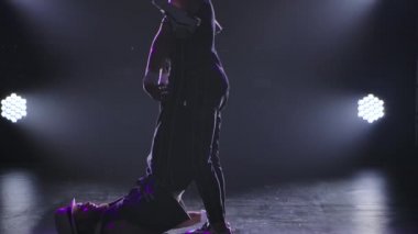 İki erkek jimnastikçi bilanço üzerinde akrobatik numaralar yapıyor. Siyah arka planda spot ışıkları olan iki adamın siluetleri. Ağır çekimde kapat..
