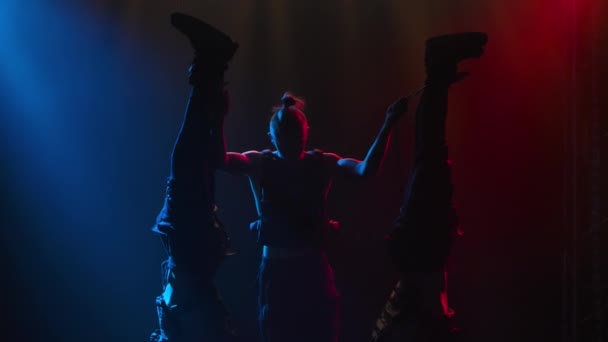 Un grup de gimnaste acrobatice de sex masculin demonstrează o poziție frumoasă de echilibru. O cascadorie acrobatică complexă realizată în studio cu lumini de neon. Siluetele se închid. Slow motion . — Videoclip de stoc