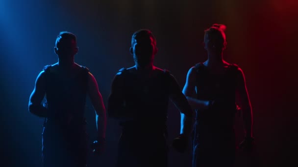Performance di ginnaste muscolose maschili in uno studio buio con luce al neon. Gli uomini dimostrano la loro forza mostrando acrobazie acrobatiche. Chiudere al rallentatore. — Video Stock