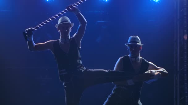 Un grup de gimnaste profesionale de sex masculin efectuează exerciții acrobatice provocatoare pentru a demonstra echilibrul și puterea. Împușcat într-un studio întunecat cu lumină albastră în fundal. Mişcare lentă. Close up — Videoclip de stoc
