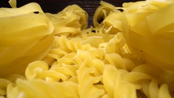 Встановіть сиру макаронні вироби на дерев'яний стіл. Ковзання вперед над різними видами макаронних виробів. Супер макрозйомка . — стокове відео