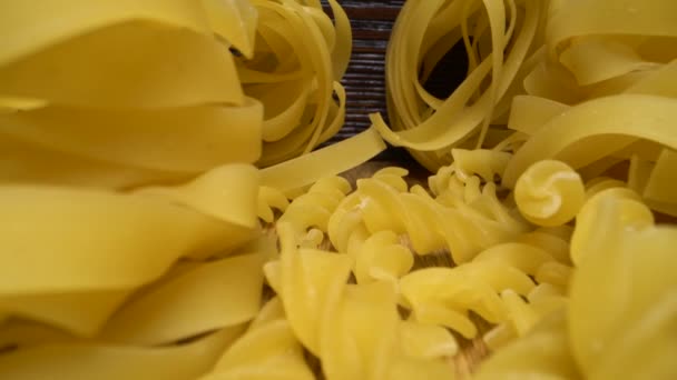 Super macro shot di pasta cruda su tavola di legno. Scorrimento verticale in avanti su diversi tipi di pasta. — Video Stock