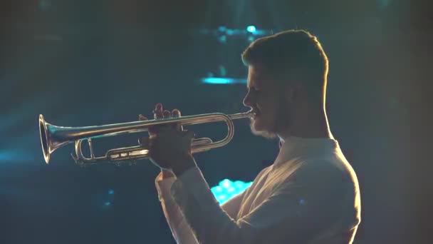 Vista lateral homem em uma camisa branca toca trompete no estúdio com luzes dinâmicas brilhantes.. Close-up de mãos masculinas e instrumento de latão. Concerto musical. — Vídeo de Stock