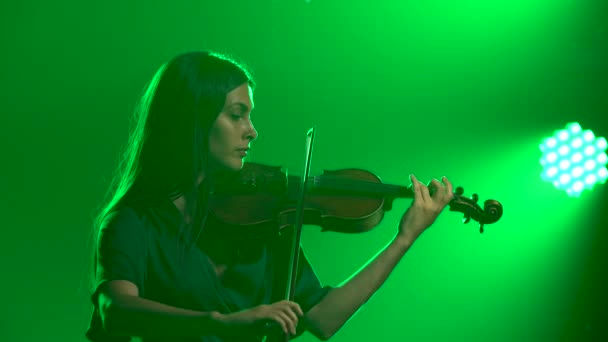 一个迷人的专业小提琴手会拉小提琴.在一个有绿光的烟雾弥漫的工作室里排练。靠近点. — 图库视频影像