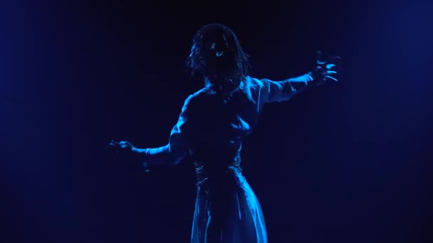 Mooie jonge actrice naar het beeld van Jeanne Dark danst op het podium met een zwaard. Silhouet van een slanke body in een sprankelende hoofdtooi tegen een achtergrond van blauwe spots. Sluiten.. — Stockvideo