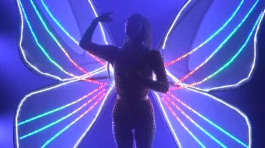 Parlayan kanatları olan bir kelebek kadar aktristim. Stüdyoda mor neon ışıklarıyla dans eden bir kadın. Kapat..