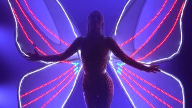 Parlayan kanatları olan bir kelebek kadar aktristim. Stüdyoda mor neon ışıklarıyla dans eden bir kadın. Kapat..