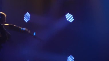 Zırhlı bir şövalyenin silueti iki kılıcı profesyonel olarak kullandığını gösterir. Duman ve mavi ışıklı karanlık stüdyo. Ağır çekim. Kapat..