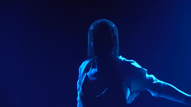 Silhuett av charmig ung kvinna i bild av Jeanne Dark dansar på scenen med ett svärd. Skådespelerska i en gnistrande huvudbonad mot bakgrund av blå spotlights. Närbild i slow motion. — Stockvideo