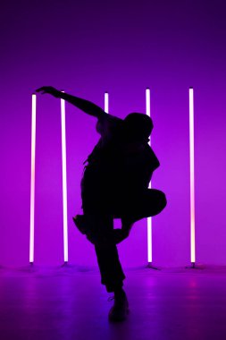 Neon lambaların arka planında hip hop elementleri yapan yakışıklı birinin portresi. Gece kulübündeki partide dans eden adamı kapat. Siluet. Dans okulu posteri.