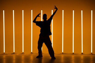 Renkli arka planda neon lambalarla hip-hop dansı yapan havalı genç break dansçı. Breakdance okulu posteri. Kapat..