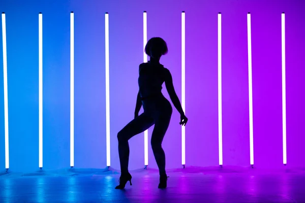 Ung snygg flicka dans i studion på en färgad bakgrund med neon belysning lampa. Musik dj affisch design. Mörk siluett. — Stockfoto