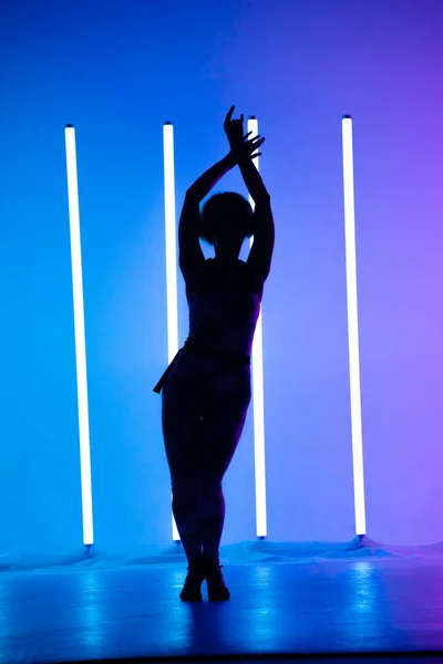Giovane ragazza elegante che balla in studio su uno sfondo colorato con lampada al neon. Disegno poster dj musicale. Silhouette scura. — Foto Stock