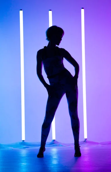 Graziosa giovane donna che balla elementi di danza moderna in studio su uno sfondo blu viola con lampada al neon. Disegno poster danza. — Foto Stock