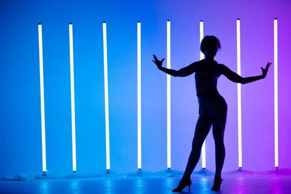 Gracieuze jonge vrouw dansende elementen van moderne dans in de studio op een blauwe paarse achtergrond met neon verlichting lamp. Dans poster ontwerp. — Stockfoto