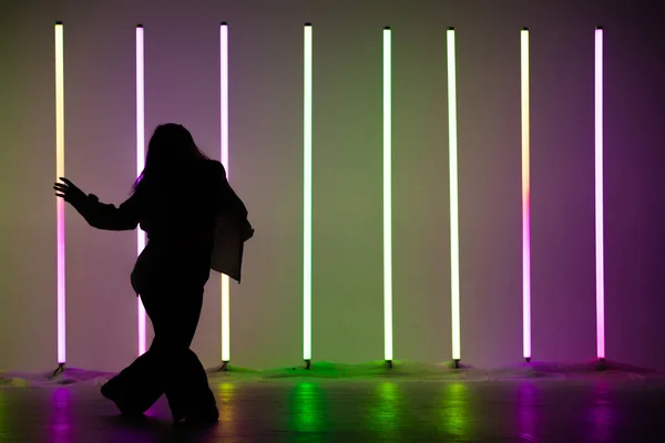 Ung snygg kvinna dansare dansar samtida i studion på en färgstark bakgrund med neon belysning röret. — Stockfoto