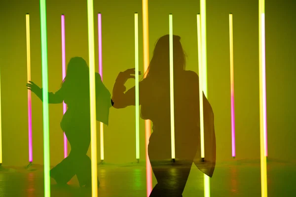 Collage av skuggor graciösa unga kvinna dansande element av modern dans i studion på en färgstark bakgrund med neon belysning lampa. Dansaffischdesign. — Stockfoto