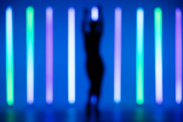 Suddig ram ung hip-hop kvinnlig dansare utför solo i studion på en färgstark bakgrund med neon belysning röret. — Stockfoto