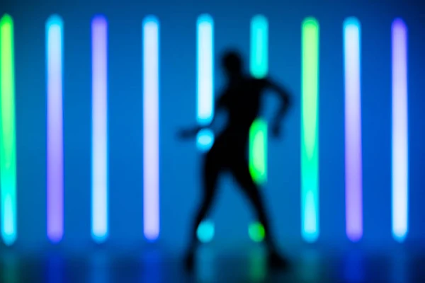 Bulanık çerçeveli genç hip-hop kadın dansçısı stüdyoda neon ışıklı bir arka planda solo performans sergiliyor.. — Stok fotoğraf