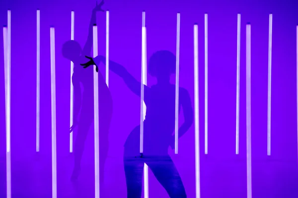 Коллаж теней спортивной девушки-танцовщицы, исполняющей соло в студии на красочном фоне с неоновой лампой. Танцевальный плакат. — стоковое фото