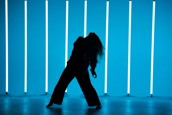 Pretty young woman dancer in a youth fashion streetwear dancing contemporary in the studio on a colorful background with neon lighting tube in disco style. Dance color poster. — Stock Photo, Image