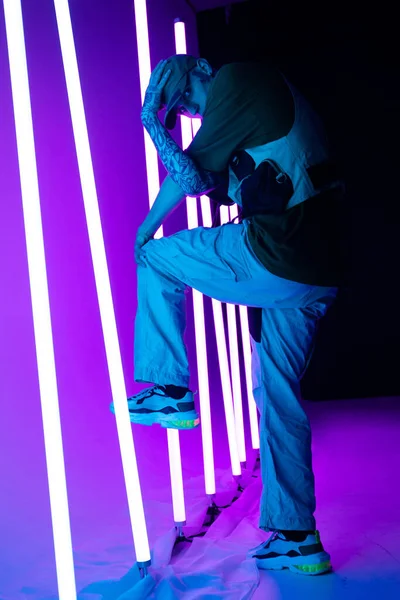Filmový portrét stylového mladíka v neonově osvětlené místnosti. Geometrické čáry neonové lampy. Jasné neonové barvy. Mládežnická kultura breakdance, festivalového stylu a hudební koncepce. — Stock fotografie
