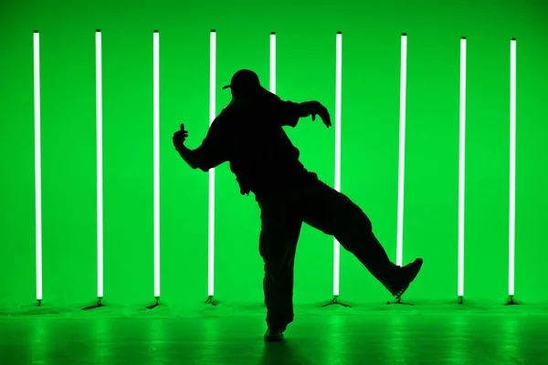 グリーンを基調としたネオンランプでクラブシーンでヒップホップスタイルでソロパフォーマンスを行う男のシルエット。閉めろ。ダンススクールポスター. — ストック写真