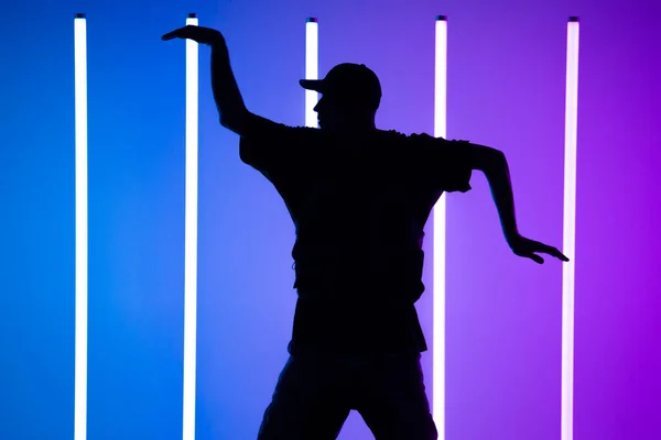 Een man die hedendaagse straatdans danst in de studio. Neon licht buis achtergrond. Acrobatische bboydanser. Schoolposter voor breakdancing. Sluiten.. — Stockfoto