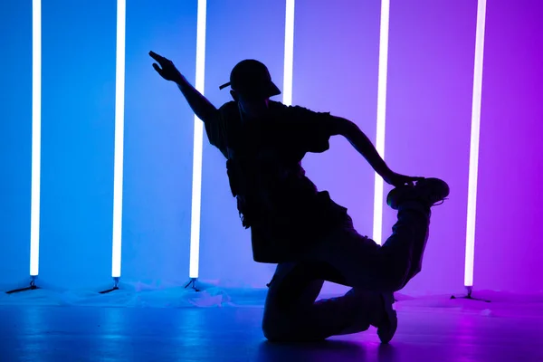 年轻英俊的男人穿着时髦的衣服跳霹雳.霓虹灯管背景图.杂技男孩舞蹈家。霹雳学校海报。靠近点. — 图库照片